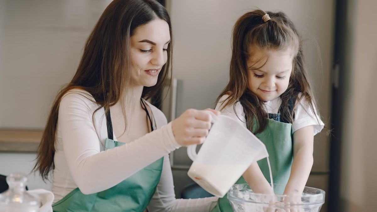 A loving mother and daughter sharing a joyful moment while baking in the kitchen together.